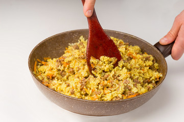 Frying pan full of yellow rice minced meat on white