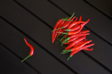Red hot chilli pods lie on black wooden boards