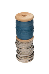 Rows of coins isolated on white background next to multicolored thread on wooden spool
