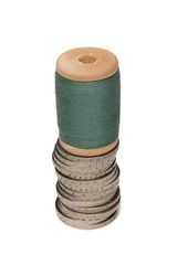 Rows of coins isolated on white background next to multicolored thread on wooden spool