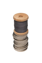 Rows of coins isolated on white background next to multicolored thread on wooden spool