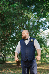 Naklejka na ściany i meble Stylish bearded fat groom in the park.
