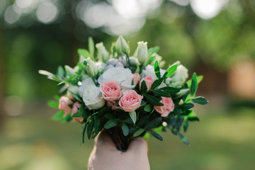 Wedding bouquet in male hand on the background of green.
