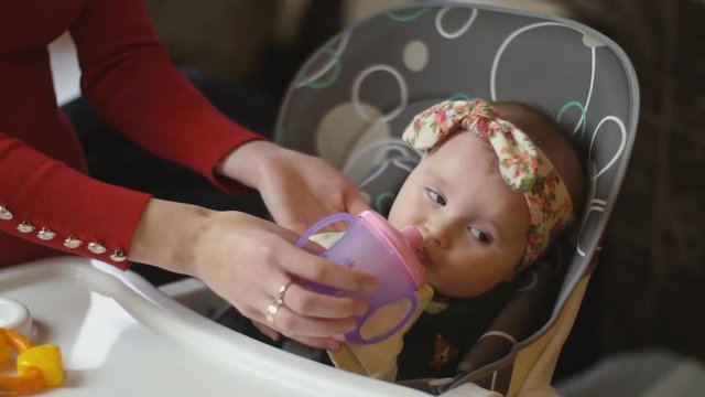 the little girl is drinking from the trough