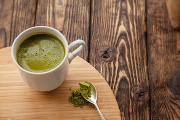cup of Matcha tea on a round wooden tray