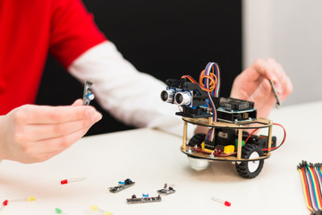 A teenager boy with his dad teacher collects a handmade metal and plastic robot. STEM education for children and teenagers, robotics and electronics. DIY. AI. STEAM.