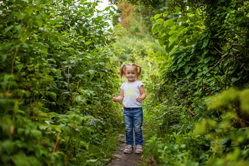 Naklejka na ściany i meble Portrait of happy cute little girl outdoor. Kid palying in park, garden, fairy forest. Happiness. Healthy preschool children summer activity