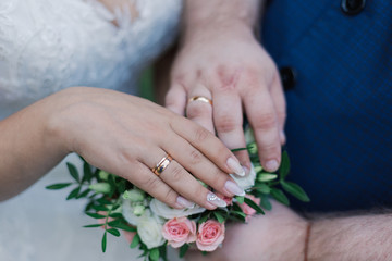 Hands oHands of newlyweds with wedding rings and a wedding bouquetf newlyweds with wedding rings and a wedding bouquet.