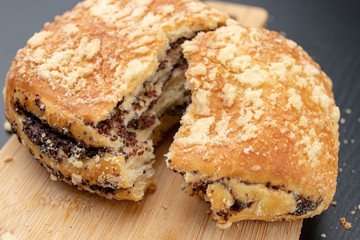 Tasty cookie broken in half. Fresh bread on a kitchen board.
