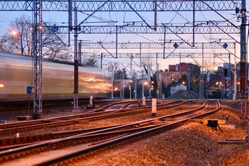 Fototapeta na wymiar Passenger train on railroad tracks at the sunrise - blurred motion