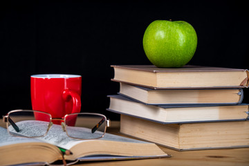 Back to school. Books, green apple, pencils and glasses on wooden table