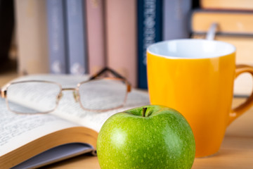 Back to school. Books, green apple, pencils and glasses on wooden table