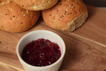 Lingonberry jam with whole grain bread and buns on the table with a cup of coffee. Close up breakfast food