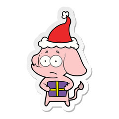 sticker cartoon of a unsure elephant with christmas present wearing santa hat