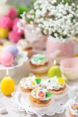 Easter cupcakes with sugar flowers, candles and eggs. Festively decorated table
