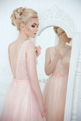 Gentle portrait of a beautiful bride with an elegant wedding hairstyle in front of a mirror.