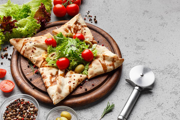 Closed pizza in star shape decorated with lettuce and cherry tomatoes