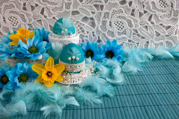 Easter composition with blue eggs, yellow and blu spring flowers and white  lace