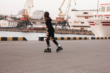 Woman skating by the sea. The girl goes rollerblading and does tricks. Caucasian woman outdoor at...