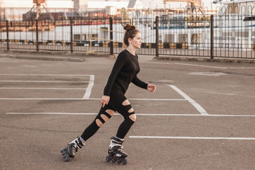 Woman skating by the sea. The girl goes rollerblading and does tricks. Caucasian woman outdoor at...