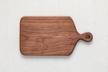 Walnut handmade wood cutting board on the linen.	