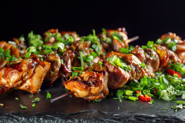 Grilled meat skewers, shish kebab on black slate.