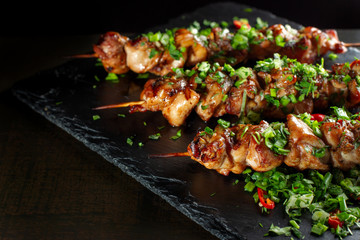 Grilled meat skewers, shish kebab on black slate.