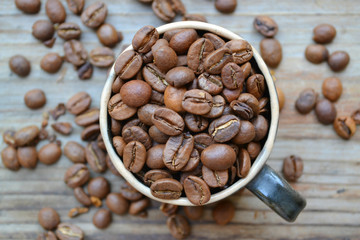 Cup full of coffee beans on wooden table