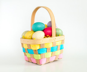 wicker Easter basket filled with colorful Easter eggs isolated on white