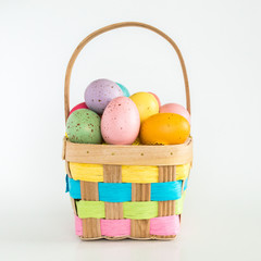 wicker Easter basket filled with colorful Easter eggs isolated on white