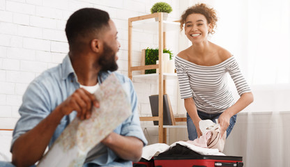 Woman packing suitcase and man studying map