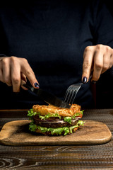 Healthy lifestyle, proper nutrition. Female hands cut a useful rice burger with vegetables, herbs and cutlet on a wooden board