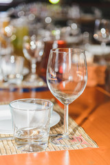 A clean glass is on the table against the background of another dish.