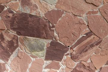 Fototapeta premium backgrounds, textures a brick wall made of natural red stone. Background made of natural stone. Red natural stone. Tile from red cobblestones with cement seams.