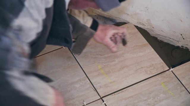 The tiler lays tiles on the floor closeup