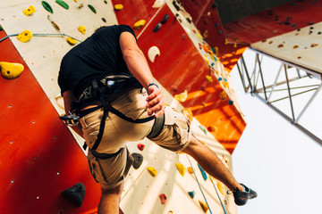 Muscular man descending down on a big wall
