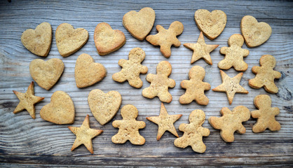Gingerbread cookies in shapes of heart, star and man with cinnamon stick and ginger root on wooden table