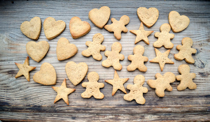 Gingerbread cookies in shapes of heart, star and man with cinnamon stick and ginger root on wooden table