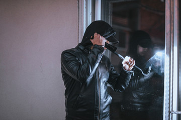 Burglar trying to open a window with a crowbar
