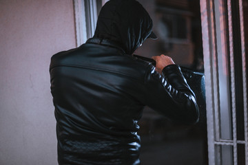 Male thief breake the window with crowbar tool