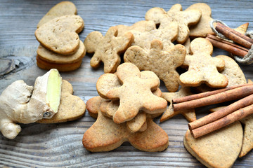 Fototapeta na wymiar Gingerbread cookies in shapes of heart, star and man with cinnamon stick and ginger root on wooden table