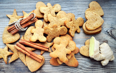 Fototapeta na wymiar Gingerbread cookies in shapes of heart, star and man with cinnamon stick and ginger root on wooden table