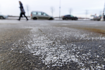 De-icing chemicals on the road. Pavement is sprinkled with technical salt or salt mixtures based on...