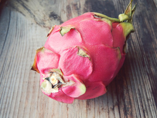 Juicy pink pitaya cut in two pieces on wooden table closeup