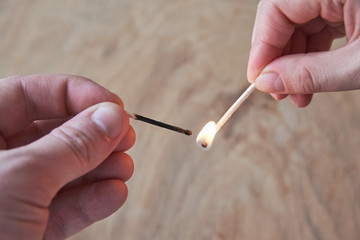 The hand of a man and a woman hold burning matches