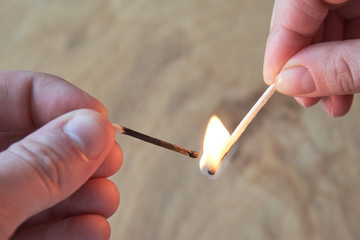 The hand of a man and a woman hold burning matches