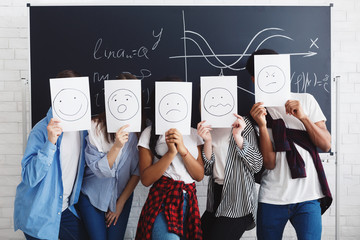 Students covering faces with papers over chalkboard