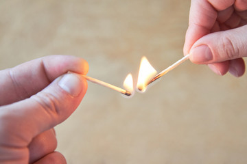 The hand of a man and a woman hold burning matches
