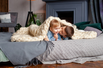 happy cute brother 6 years old and sister 3 years old in a cozy home environment on the bed...