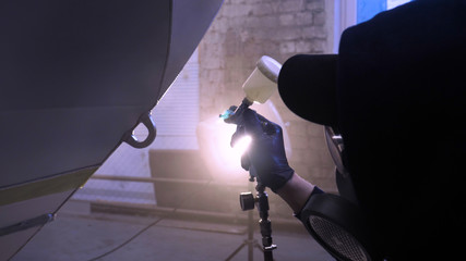 A professional guy (man) in the garage covers the yacht (transport) with a mini-jet (sprays) by...